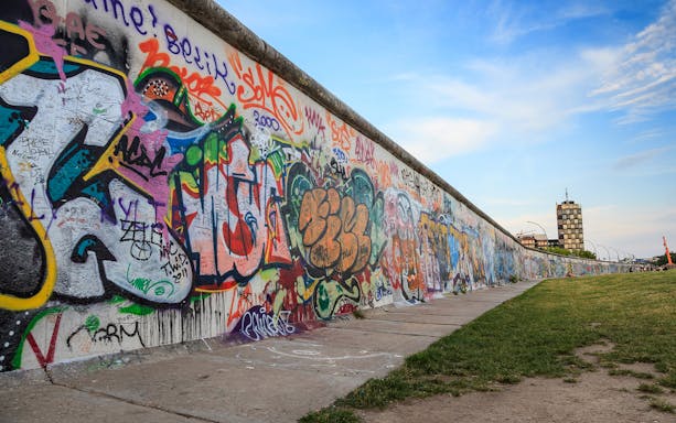 Berlin Wall with colorful graffiti, part of a self-guided audio tour in Berlin.