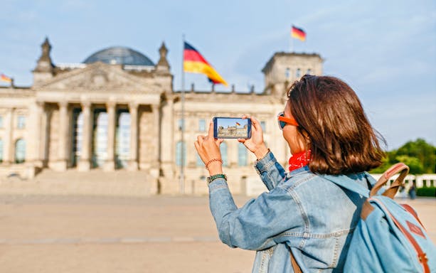 Person photographing the Reichstag building in Berlin during a self-guided audio tour.