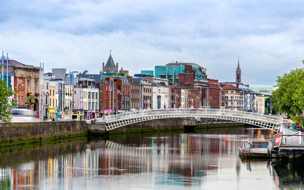 Ha'penny Bridge over River Liffey in Dublin, Ireland, with colorful buildings in the background.