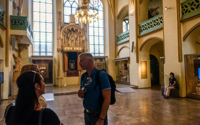 Tour group inside a historic synagogue in Prague's Jewish Quarter.