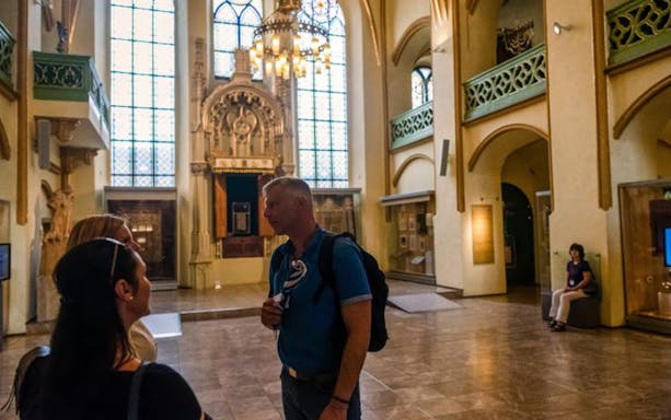 Tour group inside a historic synagogue in Prague's Jewish Quarter.
