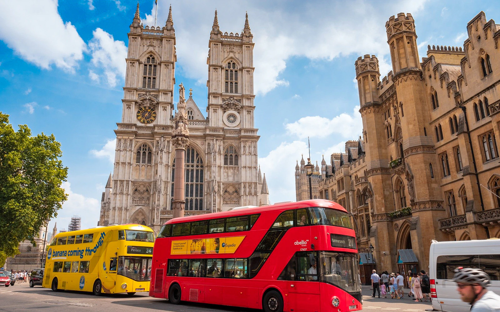 Westminster Abbey with red and yellow buses in London street scene.