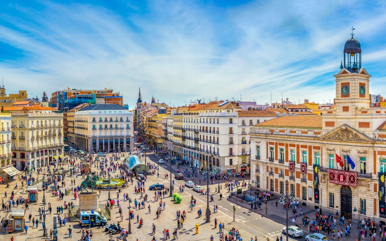 Puerta del Sol square in Madrid with the clock tower and bustling crowds.