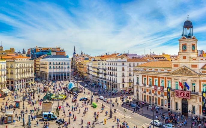 Puerta del Sol square in Madrid with the clock tower and bustling crowds.