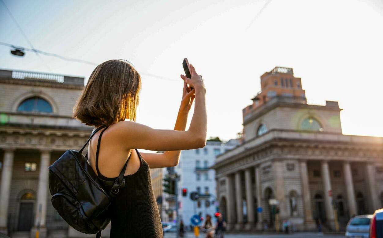 Person taking a photo of historic building in Milan during self-guided audio tour.