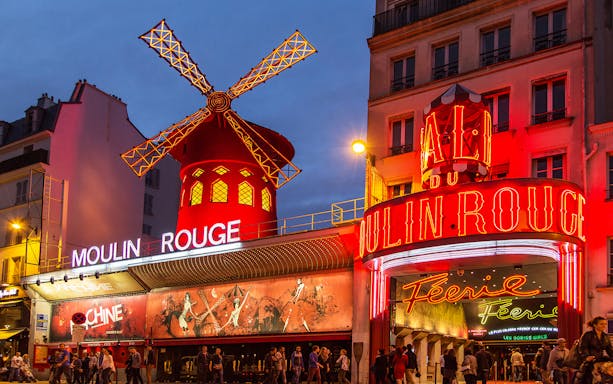 Moulin Rouge entrance illuminated at night, Paris self-guided audio tour.