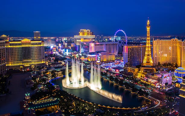 Las Vegas Strip at night with Bellagio fountains and Eiffel Tower replica.