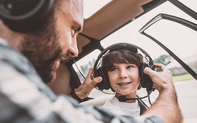 Child wearing headset in helicopter for Rundflug Berlin City tour.