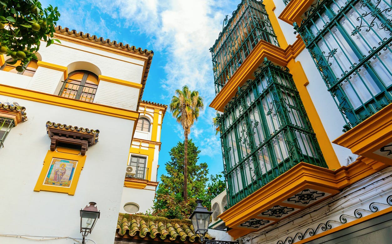 Colorful buildings and palm tree in Seville, Spain, viewed during a self-guided audio tour.