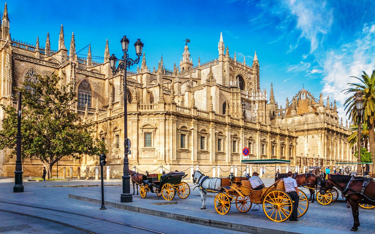 Seville Cathedral with horse-drawn carriages in front, part of a self-guided audio tour.