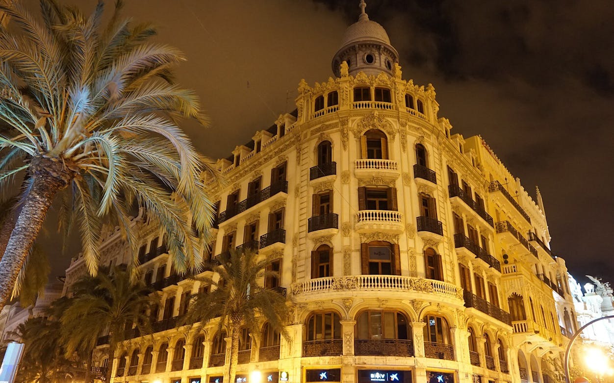 Valencia historic building with palm trees at night on self-guided audio tour.