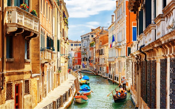 Venice canal with gondola and colorful buildings, part of a self-guided audio tour.