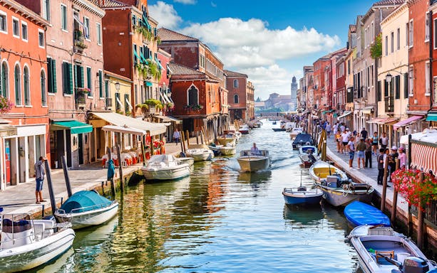 Venice canal with boats and colorful buildings, part of a self-guided audio tour.