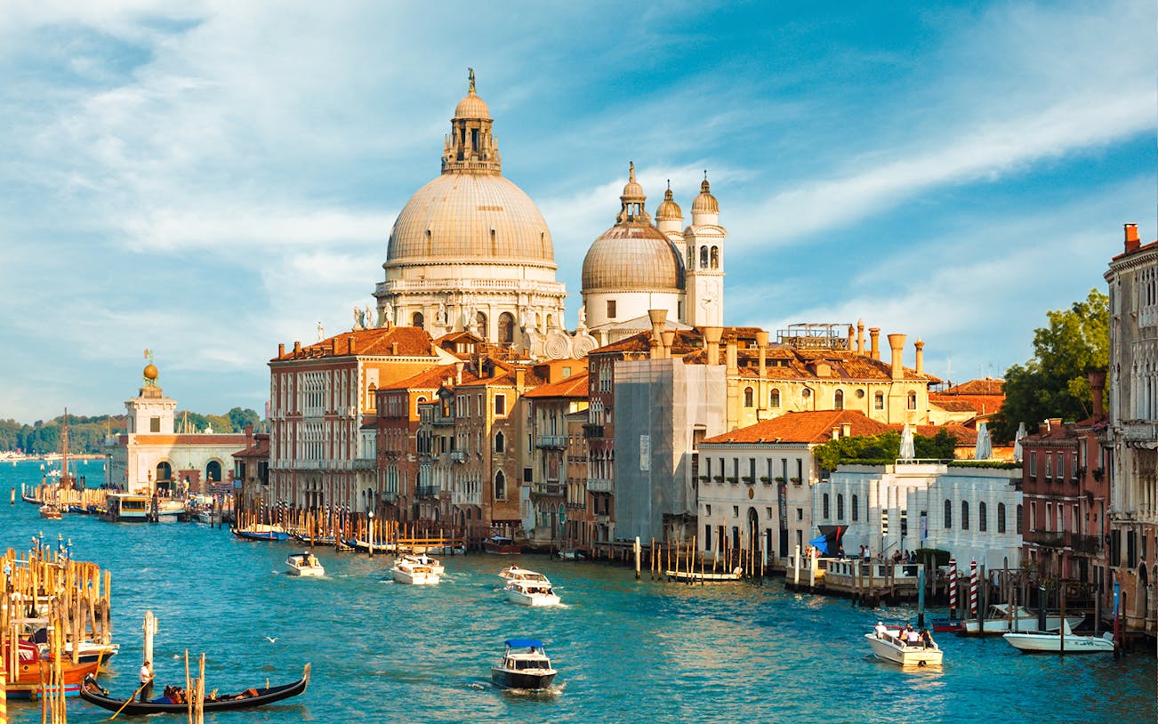 Grand Canal with Santa Maria della Salute in Venice, Italy, featuring gondolas and boats.