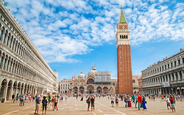 St. Mark's Square with Campanile and Basilica in Venice, Italy, crowded with tourists.