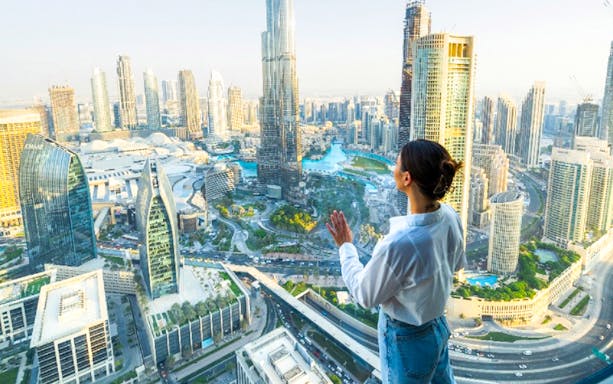 Woman enjoying panoramic view of Dubai skyline from Sky View Dubai observation deck.