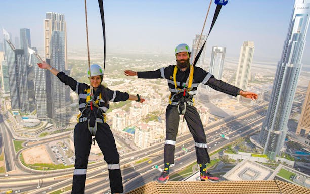 Two people harnessed on Sky View Dubai Edge Walk with cityscape in the background.