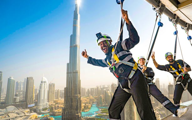People enjoying a zipline experience with a view of Burj Khalifa in Dubai.