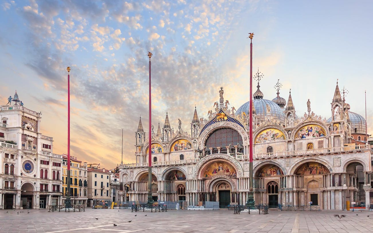 Saint Mark's Cathedral facade in Venice at sunrise, featuring ornate architecture and mosaics.