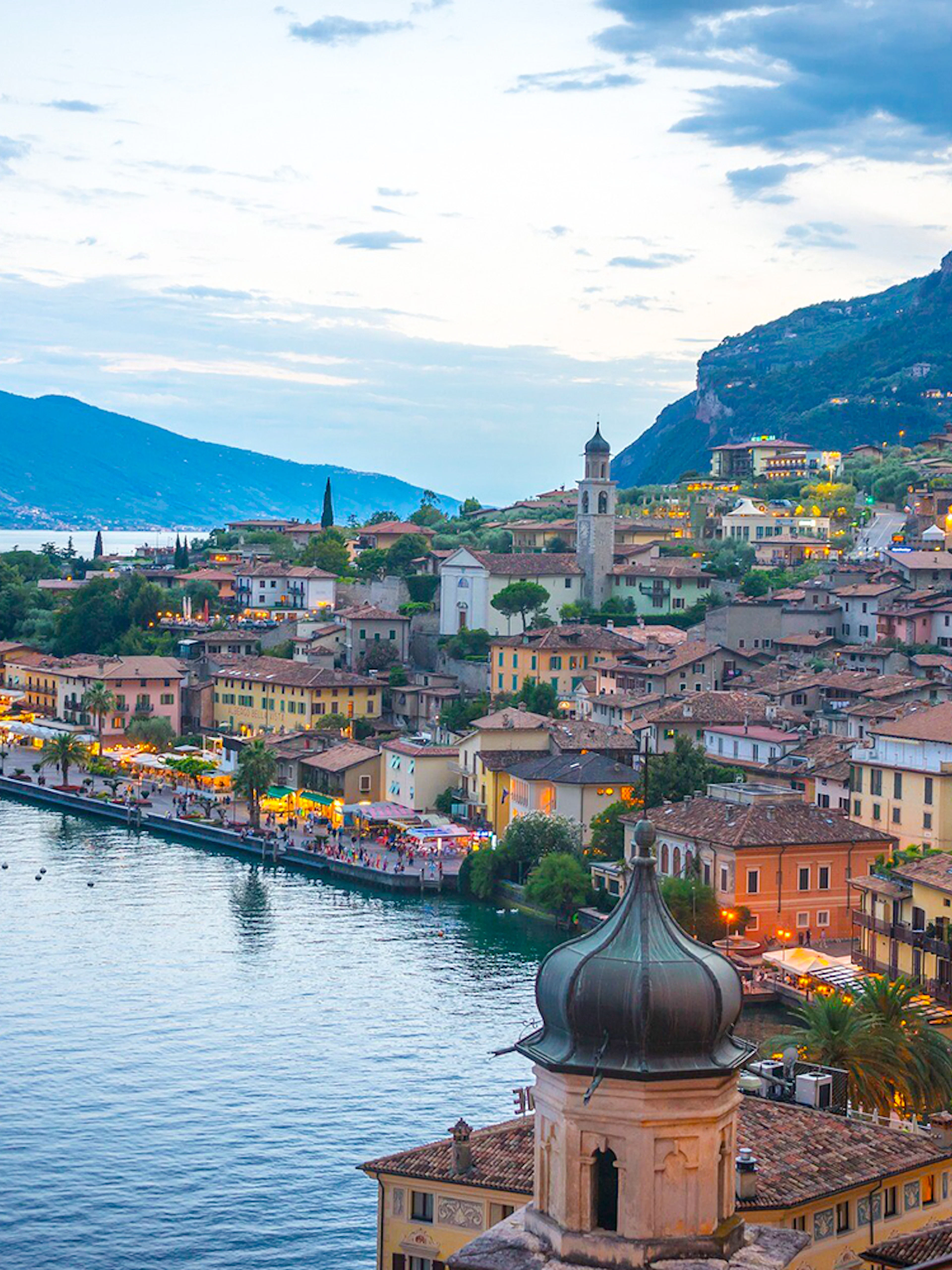 Verona and Lake Garda townscape with waterfront and mountains at dusk.