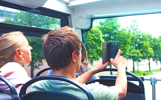 Passengers taking photos on a HopOn HopOff sightseeing bus tour.