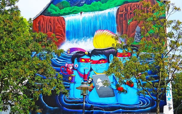 Street art mural in Sternschanze depicting vibrant characters and a waterfall.