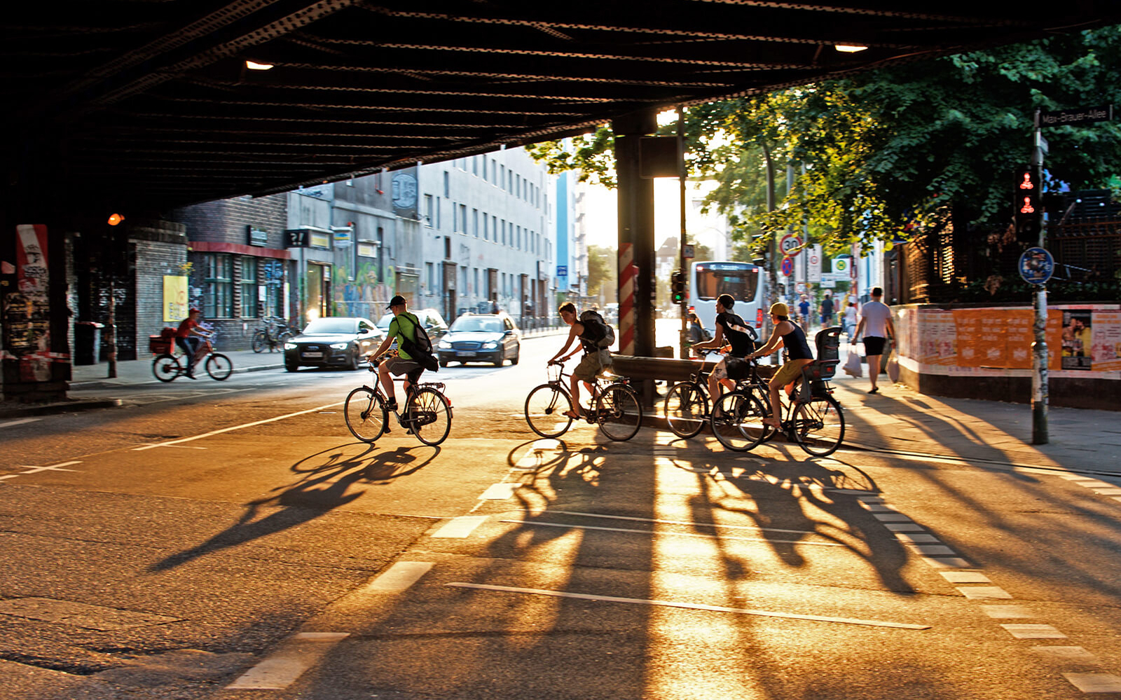 Cyclists under a bridge in Sternschanze, Hamburg, with street art and urban lifestyle elements.