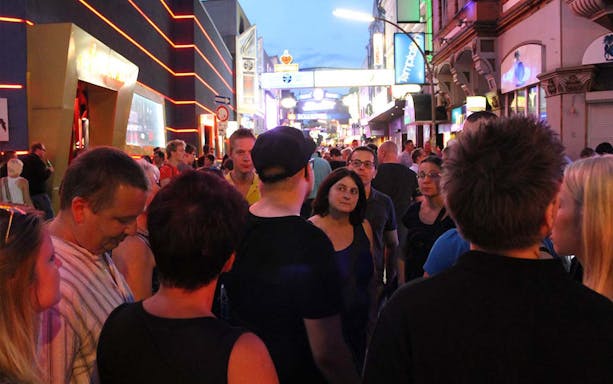 Crowd walking through Reeperbahn's illuminated street during Red Light District tour in Hamburg.