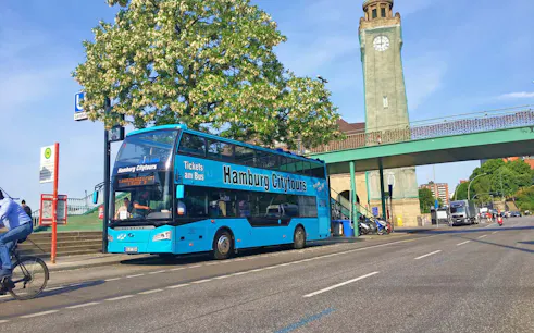 Hamburg city tour bus parked near clock tower on Reeperbahn tour route.