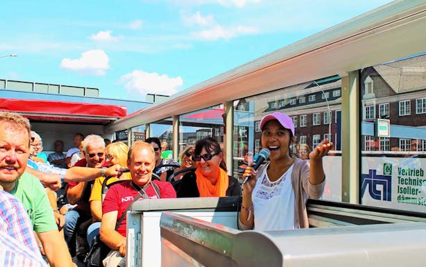Tour guide speaking to passengers on a city tour bus in Hamburg.