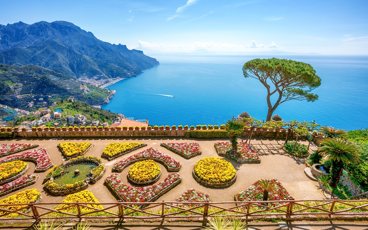 Terraced gardens overlooking the Amalfi Coast in Ravello, Italy, with views of the sea and mountains.