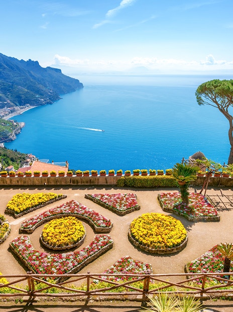 Terraced gardens overlooking the Amalfi Coast in Ravello, Italy, with views of the sea and mountains.