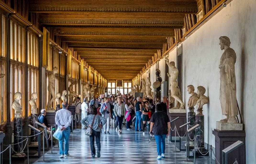 Visitors exploring the Uffizi Gallery's grand hallway lined with classical statues, capturing the essence of Renaissance art in Florence