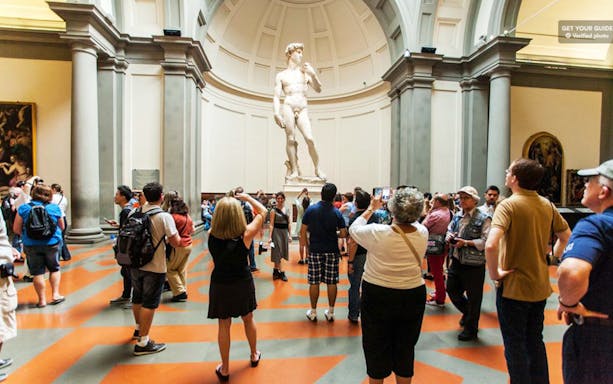 Visitors viewing Michelangelo's David at Accademia Gallery, Florence, during a guided tour.