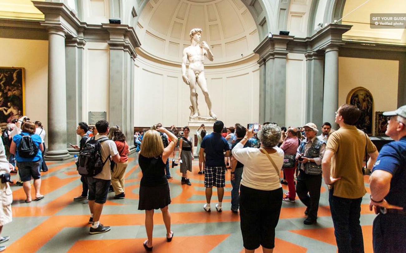 Visitors viewing Michelangelo's David at Accademia Gallery, Florence, during a guided tour.