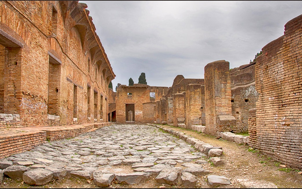 Ancient Roman ruins with stone pathway at Ostia Archaeological Park, Italy.
