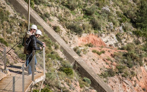 Visitors on a walkway at Caminito del Rey, Málaga, wearing safety helmets.