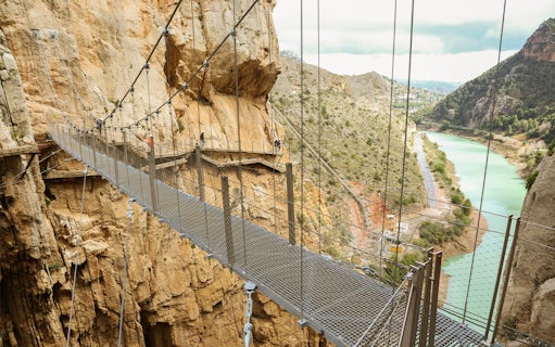Suspension bridge on Caminito del Rey trail with cliffs and river in Málaga, Spain.
