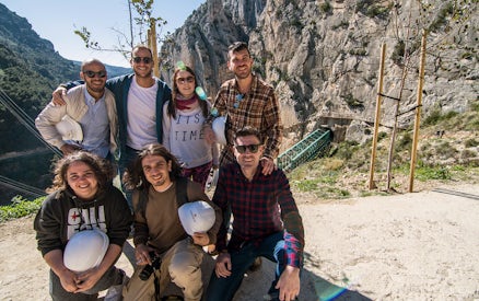 Group of tourists at Caminito del Rey trail in Málaga with helmets and scenic mountain backdrop.