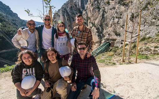 Group of tourists at Caminito del Rey trail in Málaga with helmets and scenic mountain backdrop.