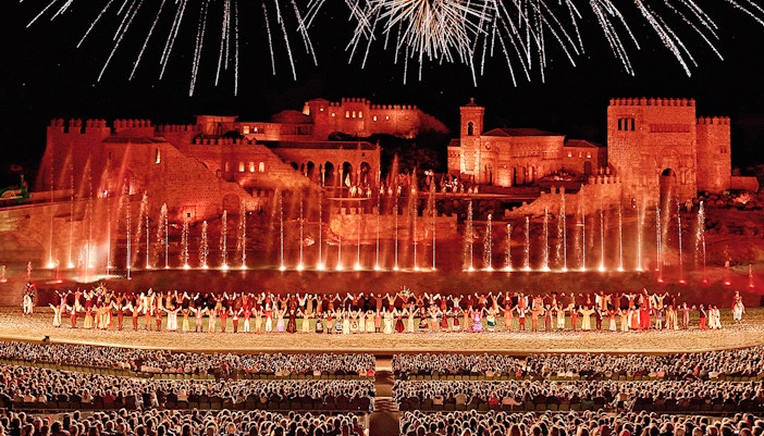 Puy du Fou España entrance at dusk with visitors gathering for El Sueño de Toledo night show, Toledo, Spain.