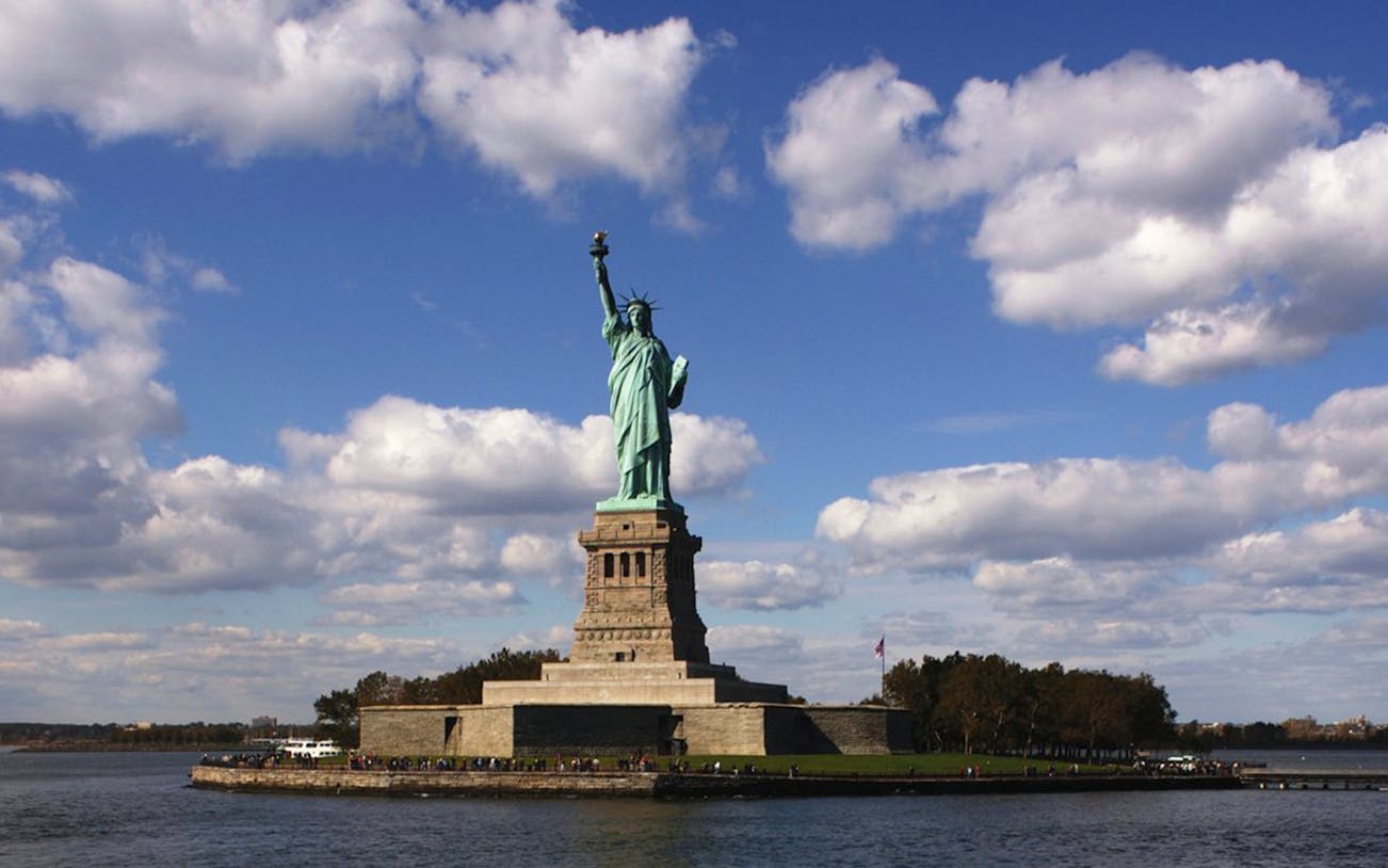 Statue of Liberty on Liberty Island with blue sky and clouds in New York City.