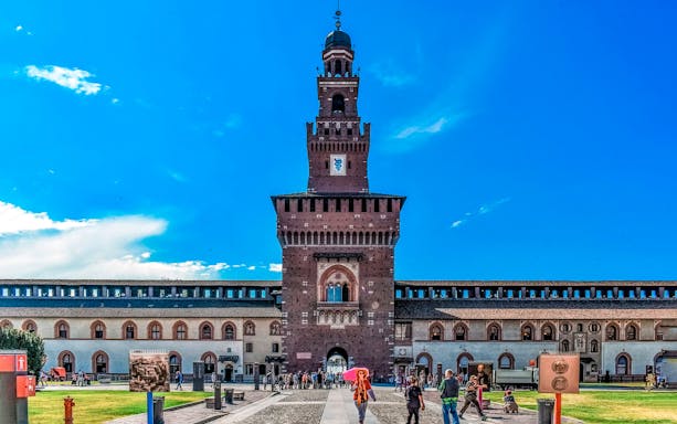 Sforza Castle entrance with visitors in Milan, Italy.