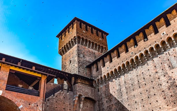 Sforza Castle tower and walls under a clear blue sky in Milan.