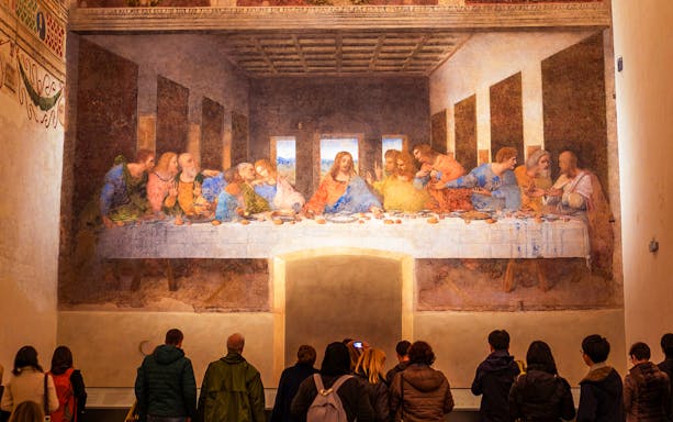 Visitors viewing Da Vinci's Last Supper mural in Milan during a guided tour.