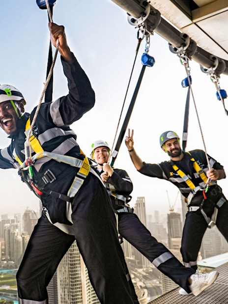 Participants on the Edge Walk at Sky Views Dubai with Burj Khalifa in the background.