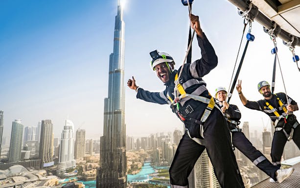 Participants on the Edge Walk at Sky Views Dubai with Burj Khalifa in the background.