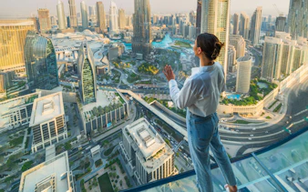 Person standing on glass platform overlooking Dubai skyline during Sky Views Edge Walk Experience.