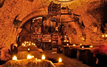 Medieval dining hall with candlelit tables set for New Year's Eve dinner.