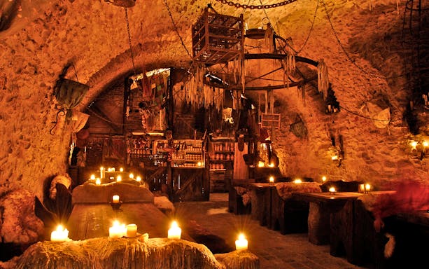 Medieval dining hall with candlelit tables set for New Year's Eve dinner.